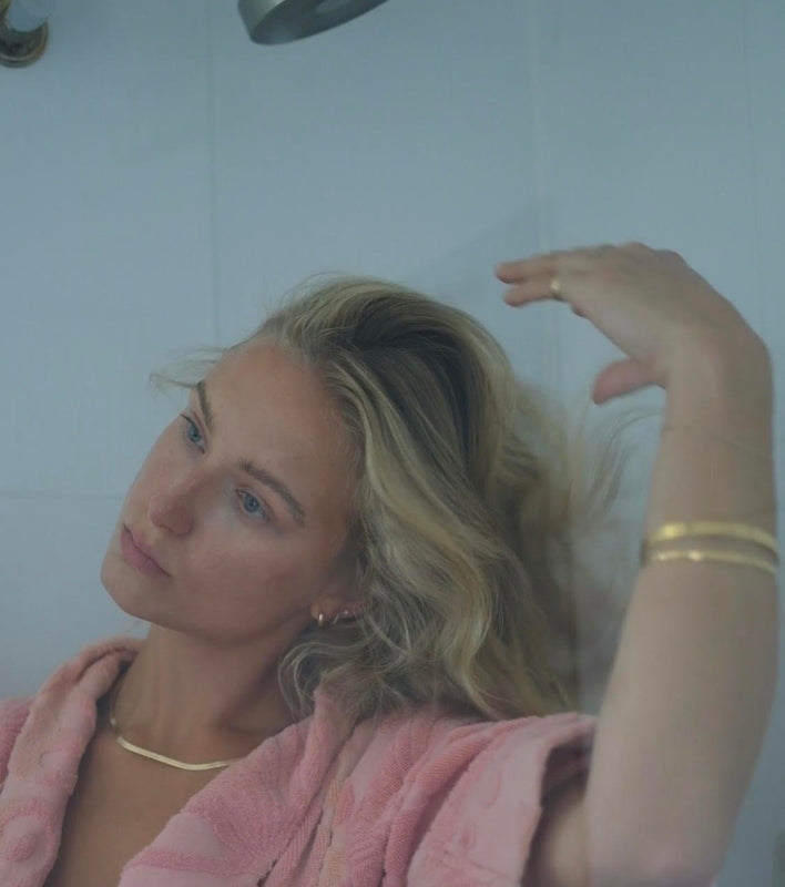 woman fluffing blonde hair after using the best products for fine hair
